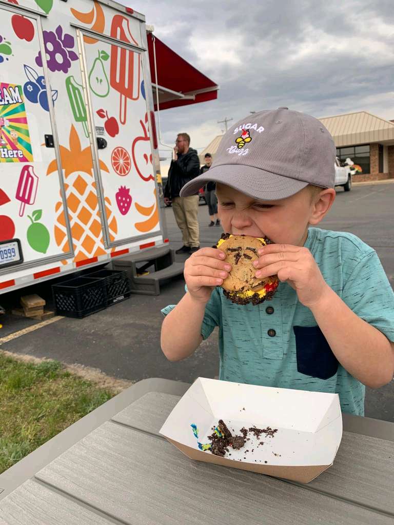 A boy eating an ice cream sandwich from Sugar Buzz.